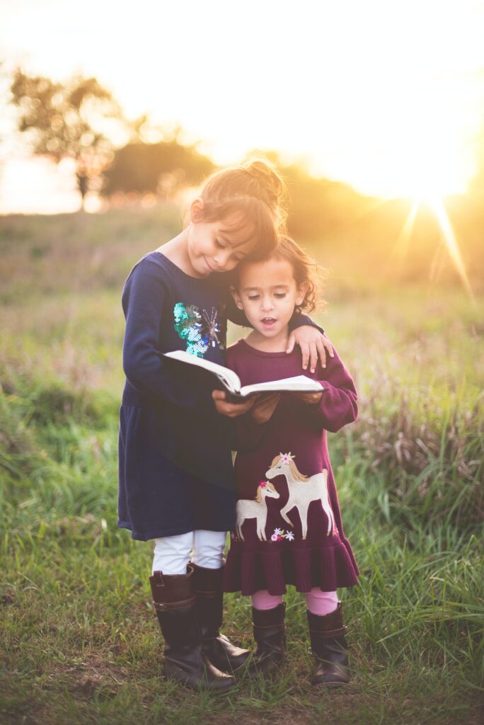 two girls reading outdoors. Free entertainment for kids 