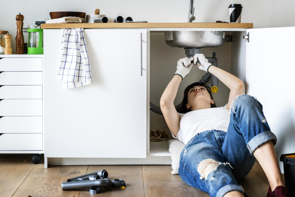 Woman fixing a sink. Doing home repairs 