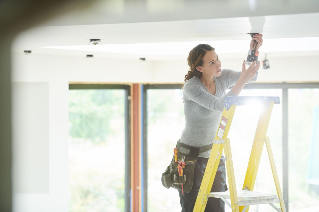 woman is replacing a lighting fixture 